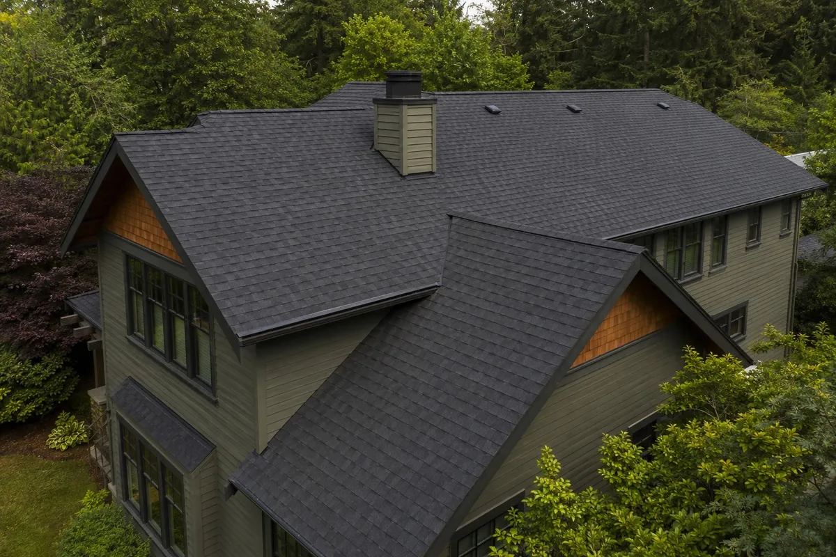 Aerial view of a completed dark asphalt shingle roof with multiple rooflines