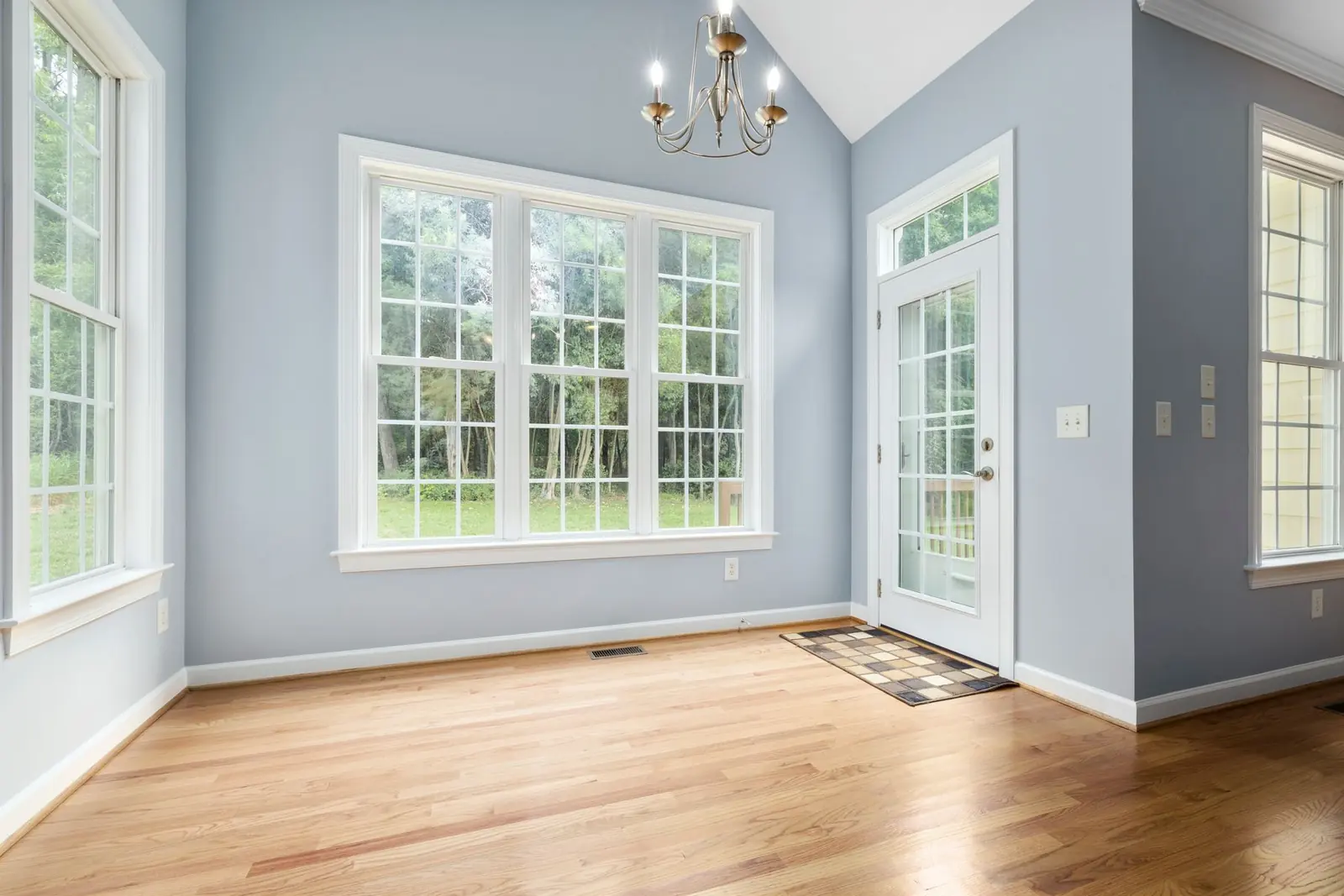 Bright residential room with three white-framed windows and finished trim